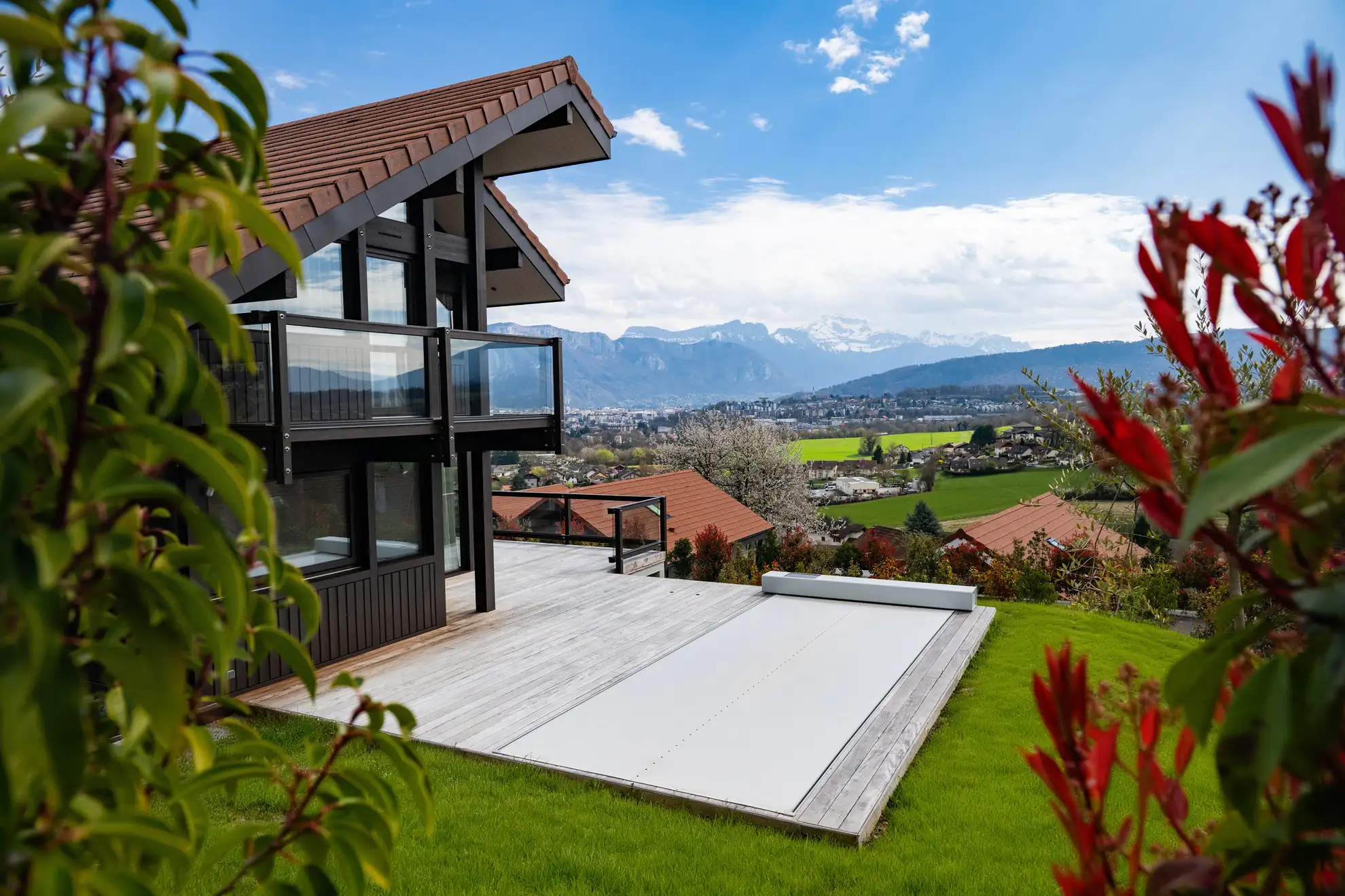 Piscine extérieure sécurisée par une couverture Coverseal, sur la terrasse d’un chalet contemporain avec vue sur les montagnes